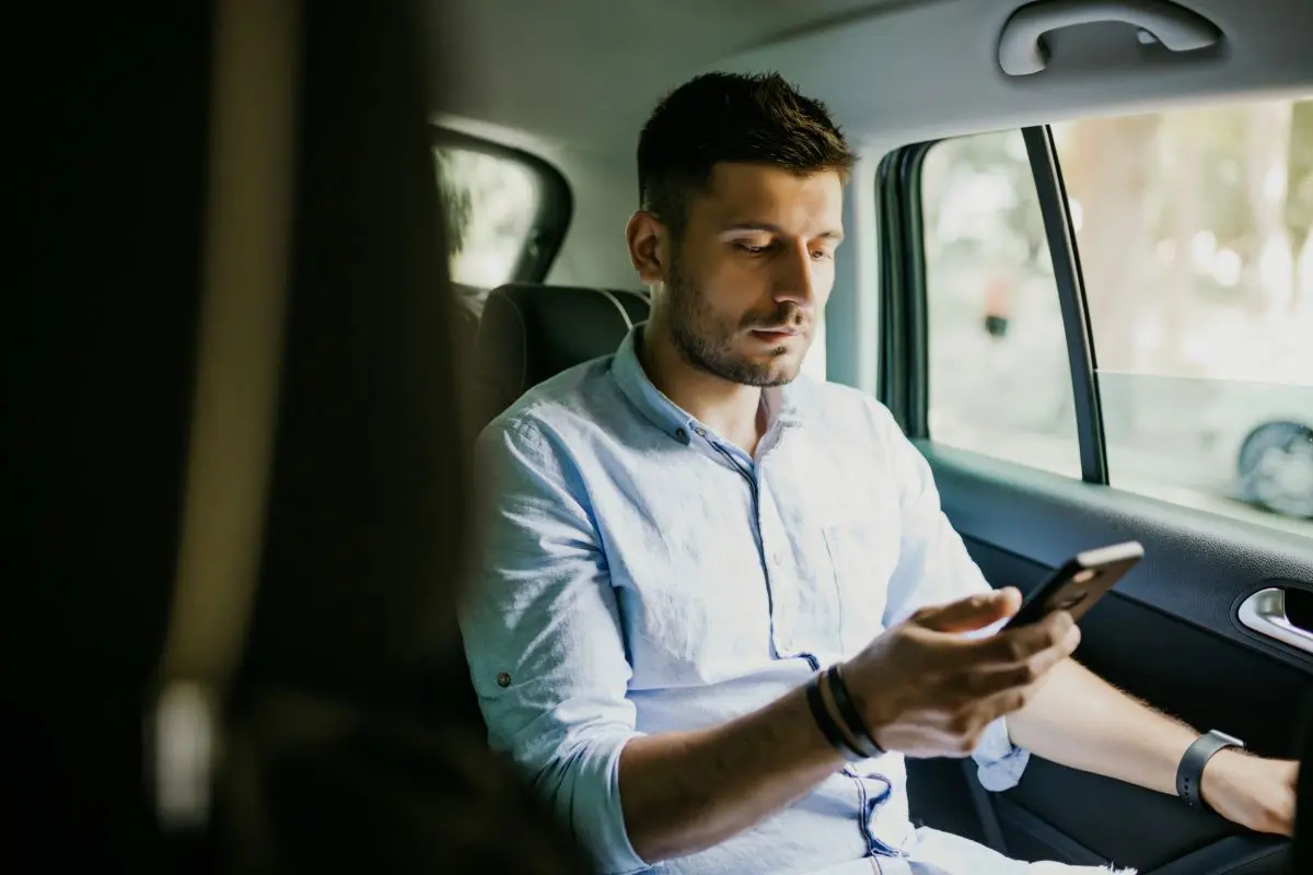 Man Sitting In Car With Cell Phone