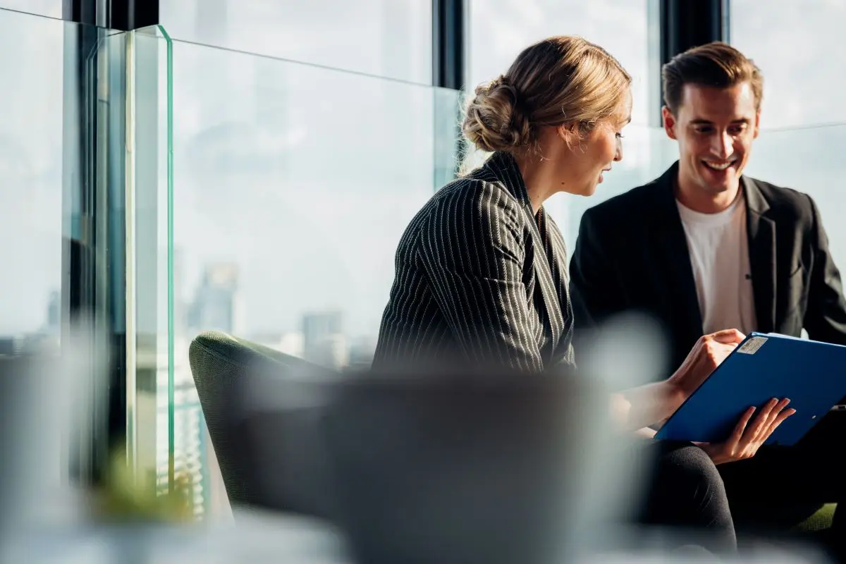 Eine Frau und ein Mann in Business-Kleidung besprechen Unterlagen.