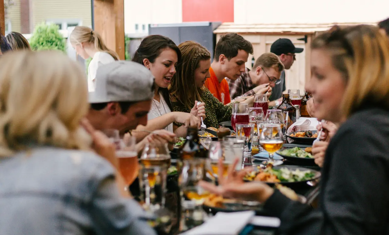 Personen essen zusammen an einem langen Tisch.