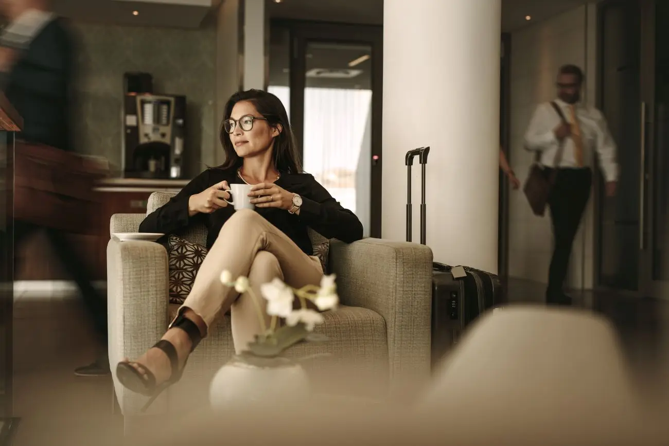 Frau sitzt mit Kaffeetasse in einer Hotel-Lobby