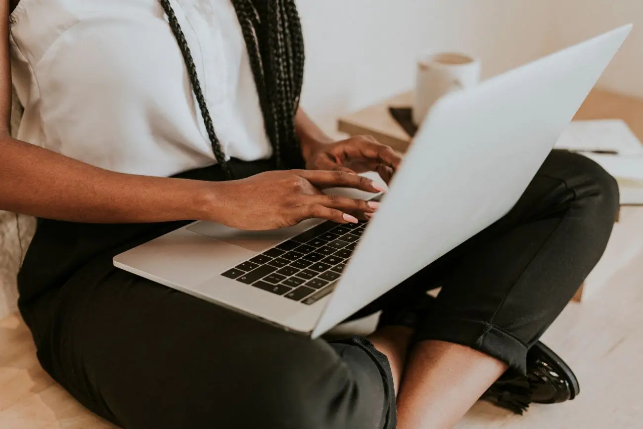 Arbeitszeiterfassung: Person im Schneidersitz tippt am Laptop.