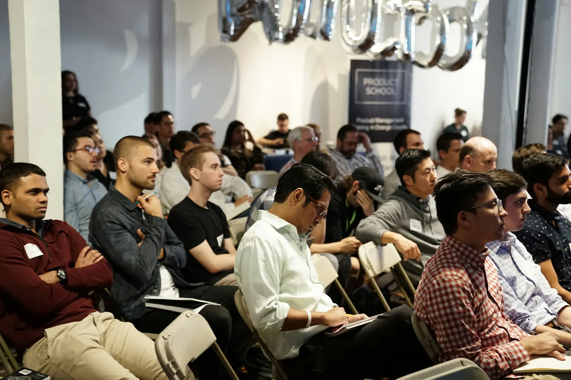 Conference audience listening to a presentation Product School GajrOEN6m4 Unsplash