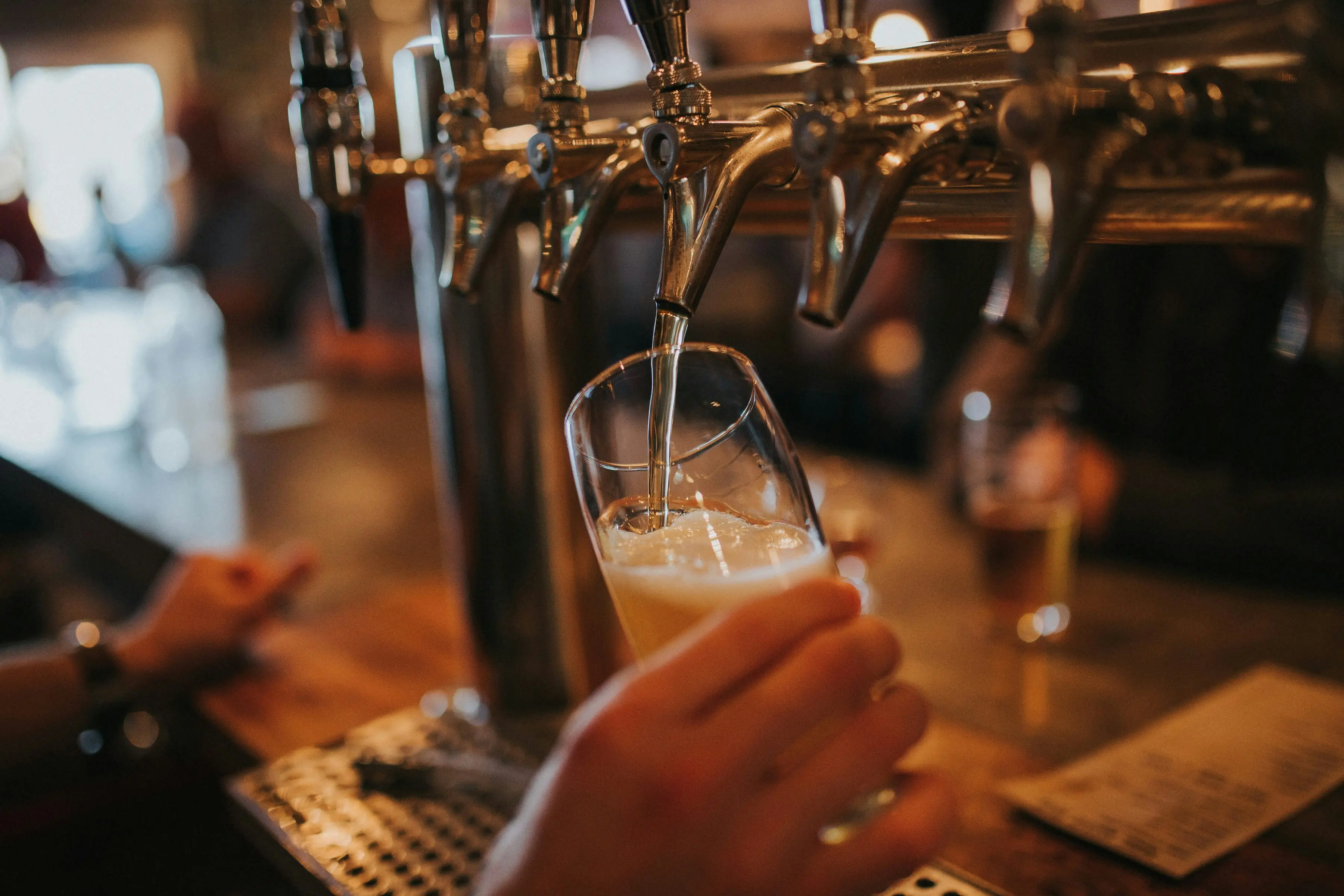 Eine Person zapft Bier in ein Glas.