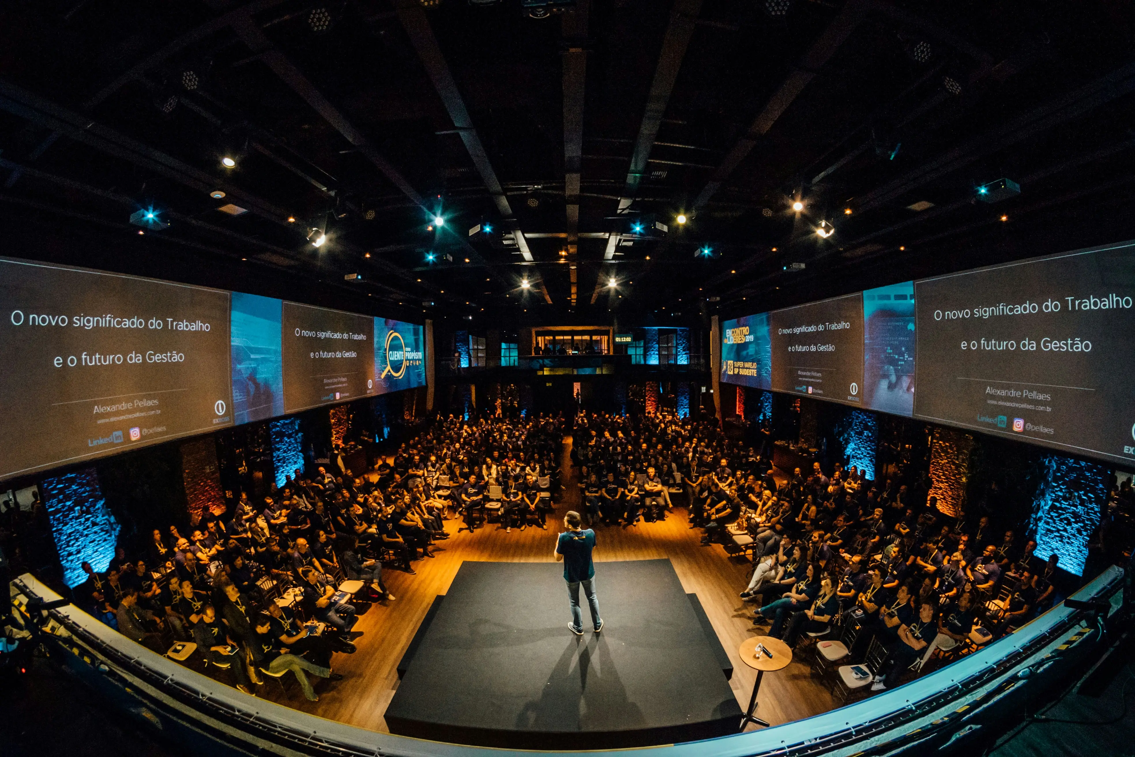 man on a stage speaks in front of a large audience