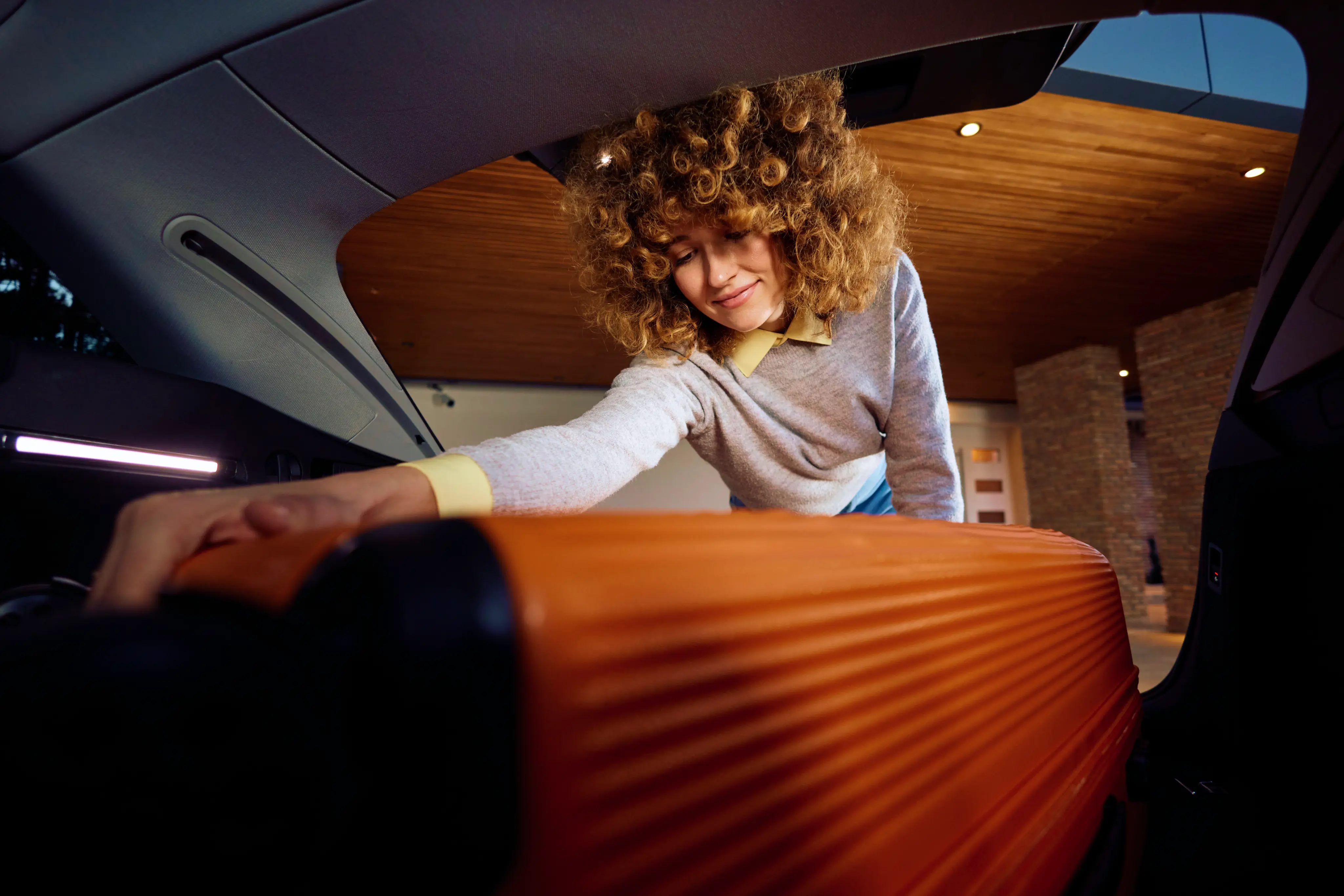 Young Woman Takes Her Suitcase From The Trunk