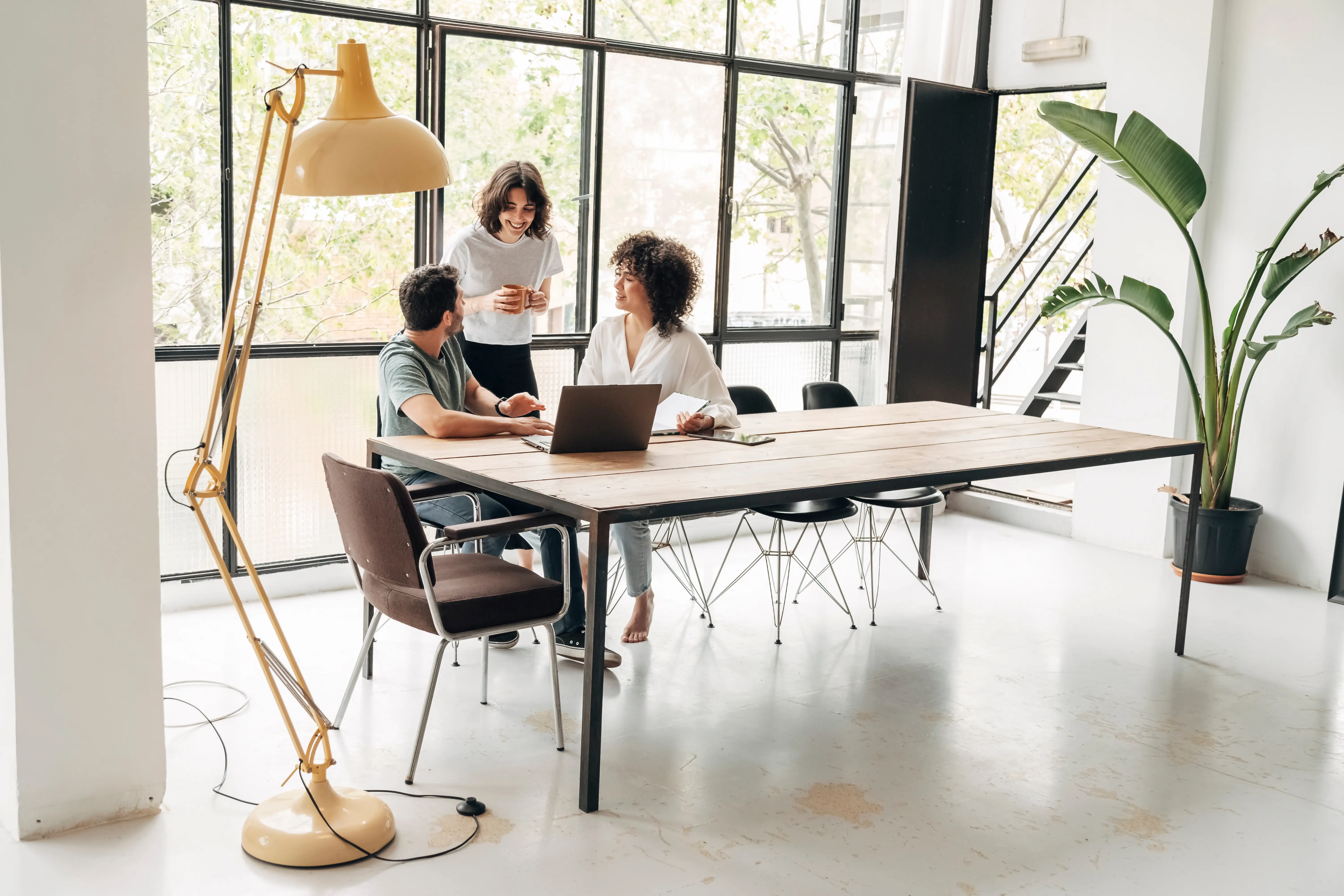Three young professionals are having a meeting at a large table.
