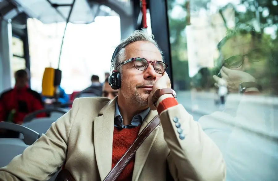 Mann mit Kopfhörern sitzt entspannt im Bus.