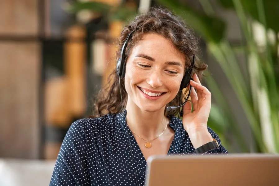 Eine lächelnde Frau telefoniert über ein Headset.