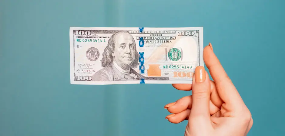 Hand Holding 100 Dollars 940x448 1