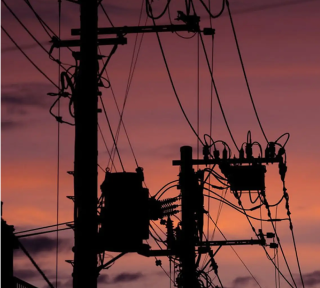 Silhouette of utility poles and power lines against a vivid pink and orange sunset sky.