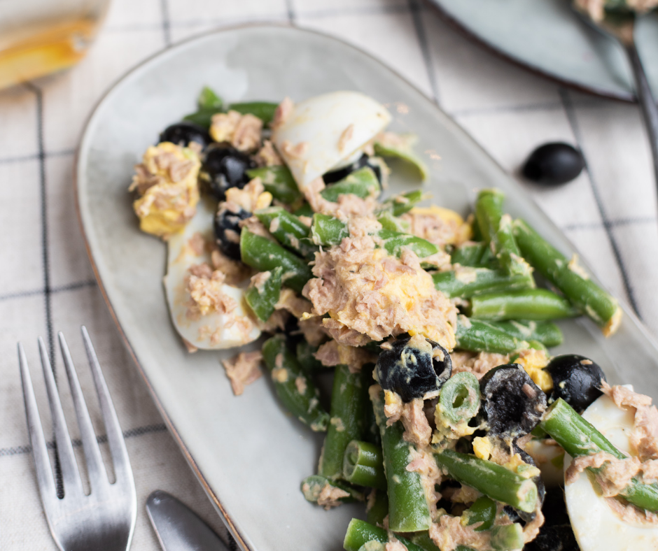 Salade met sperziebonen, tonijn, olijven en ei op een bord.
