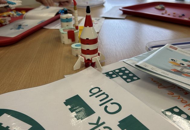 Table with Brick club banner and LEGO brick rocket