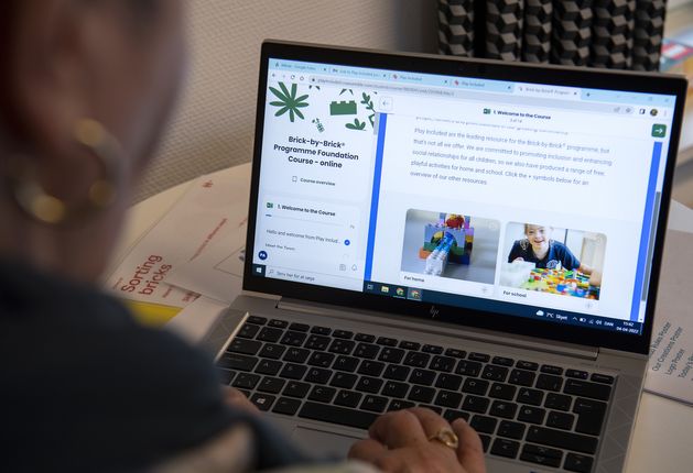 Alt text An over the shoulder photo of a certified facilitator using the Play Included Lego therapy training portal on a laptop.