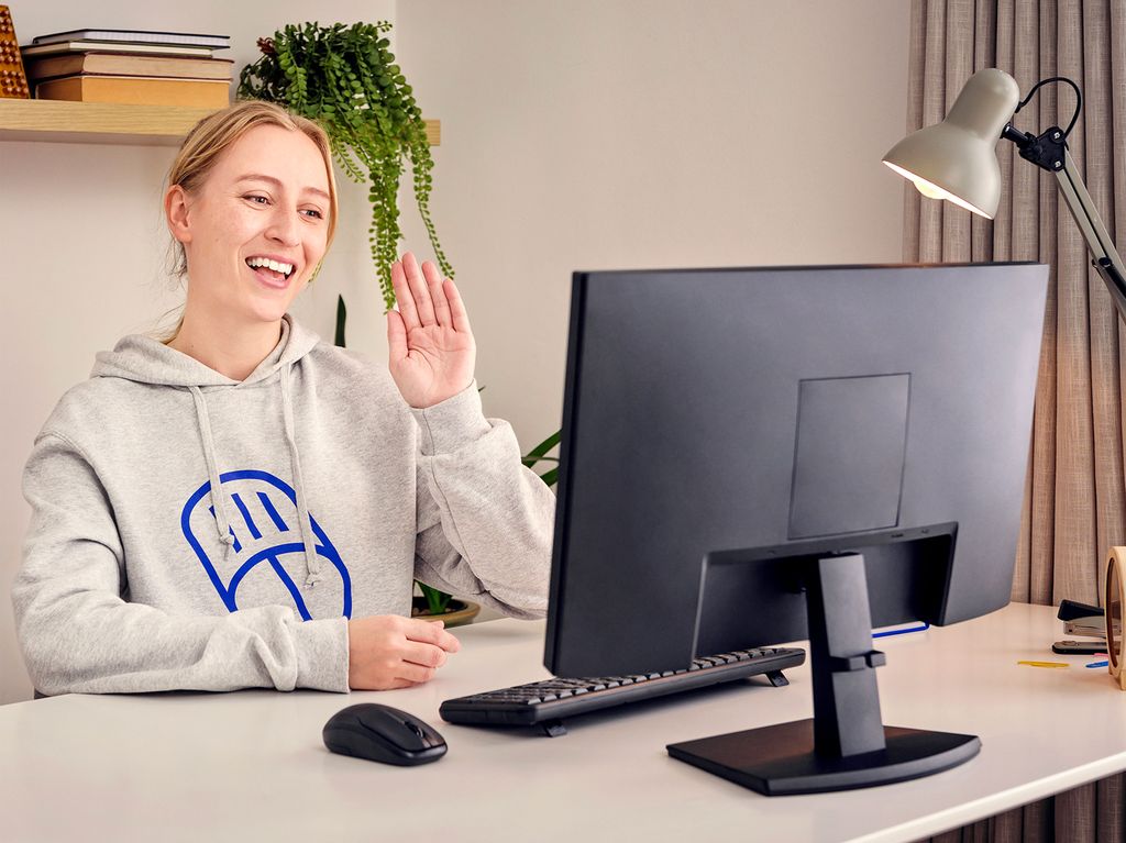 Female waving her hand at a computer.