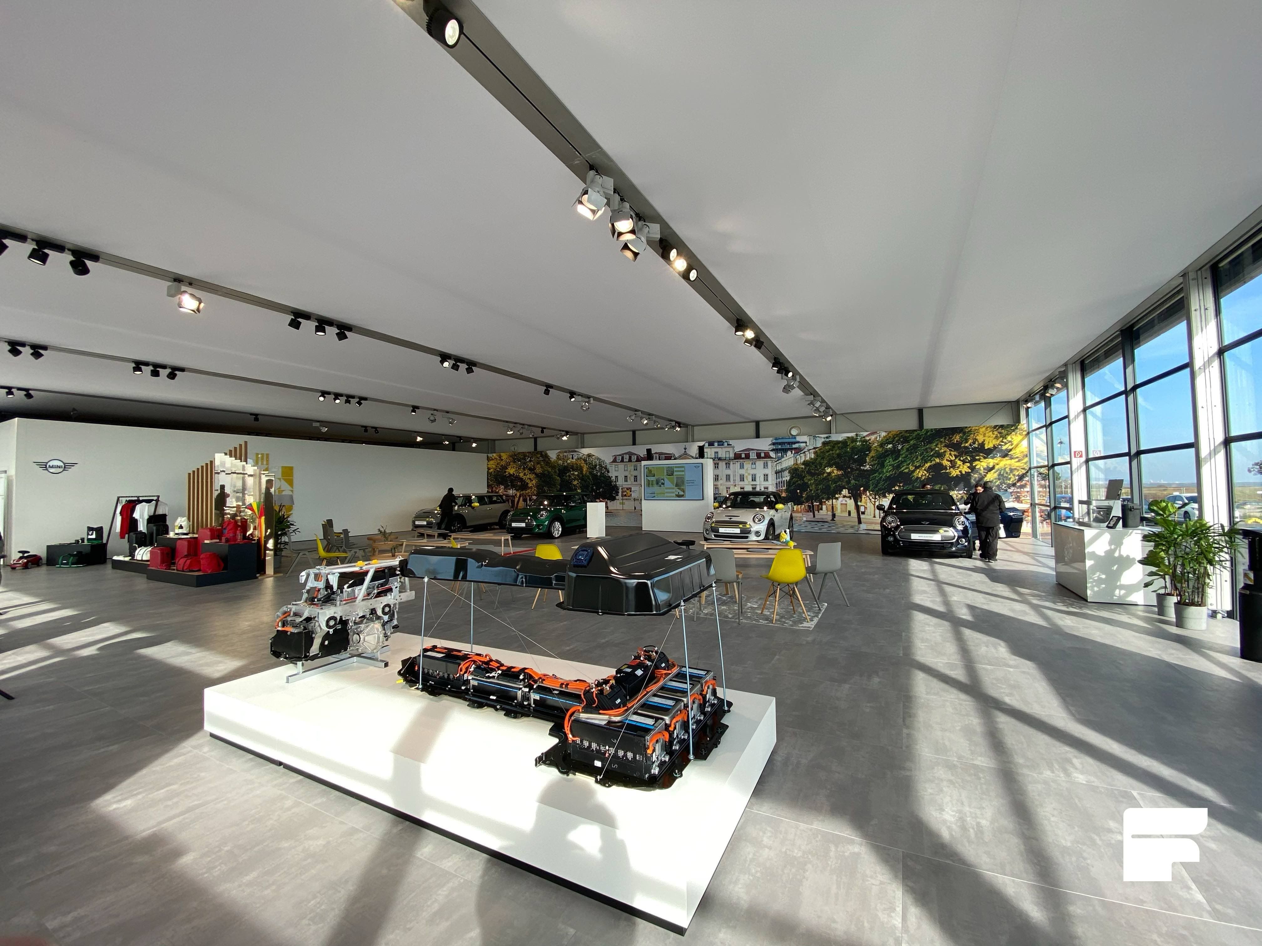 Spacious and elegantly designed temporary showroom with floor-to-ceiling glass walls, featuring automotive displays and a contemporary event setup for high-end exhibitions.