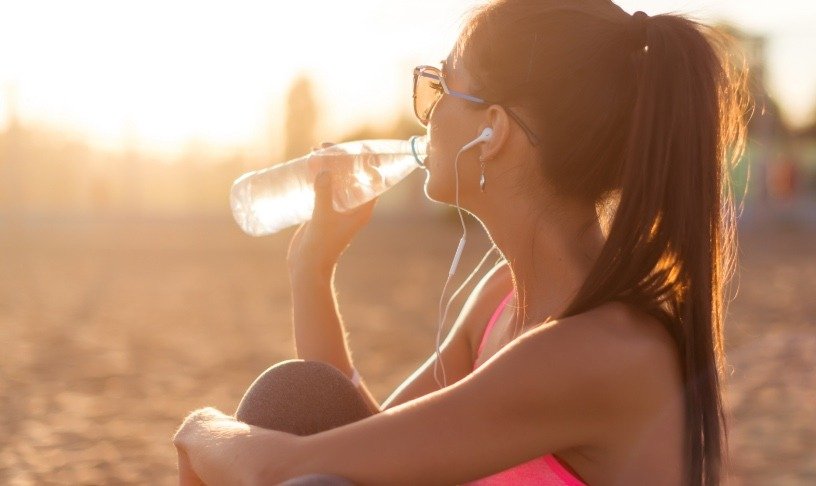 Donna che beve acqua sulla spiaggia