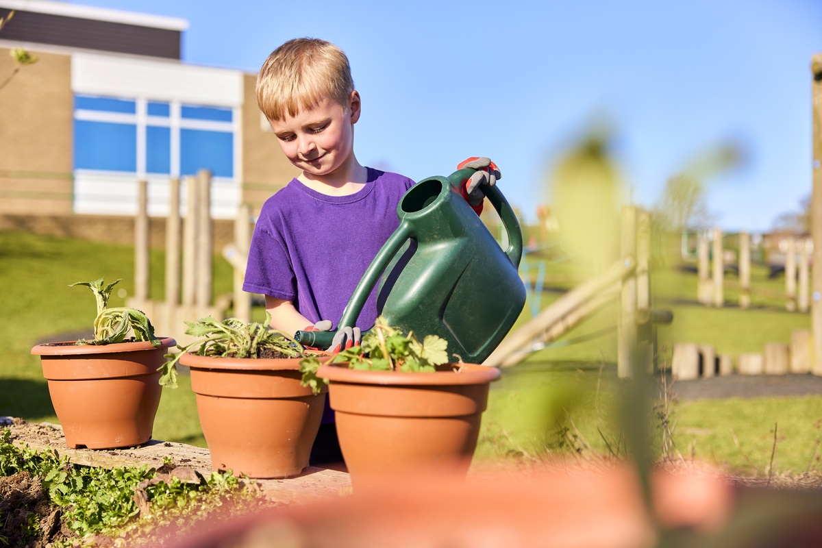 a young boy waters plants with a watering can