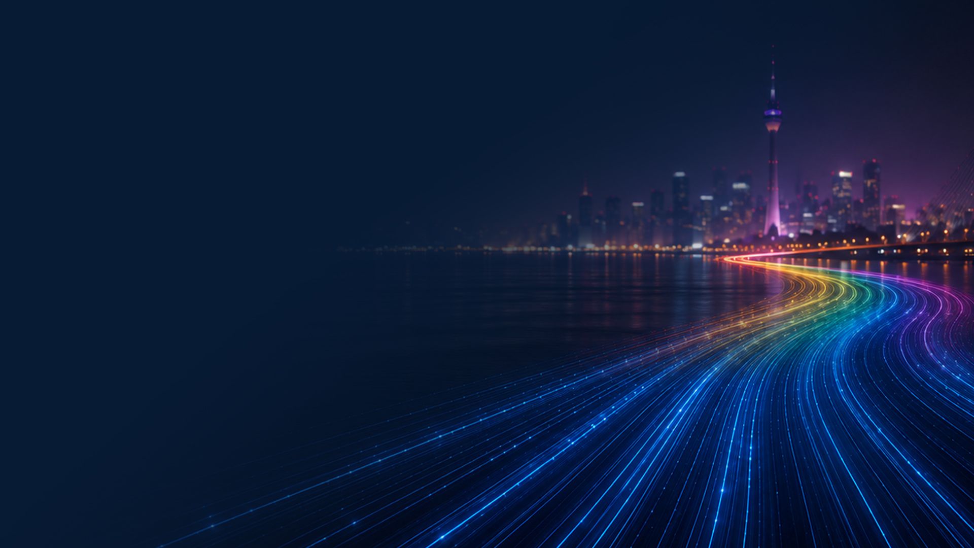 City skyline at night with a glowing tower and bright, colorful light trails reflecting on the water.