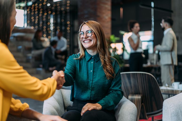 Business people shaking hands in the office. Two businesswomen handshaking during a meeting in modern office.