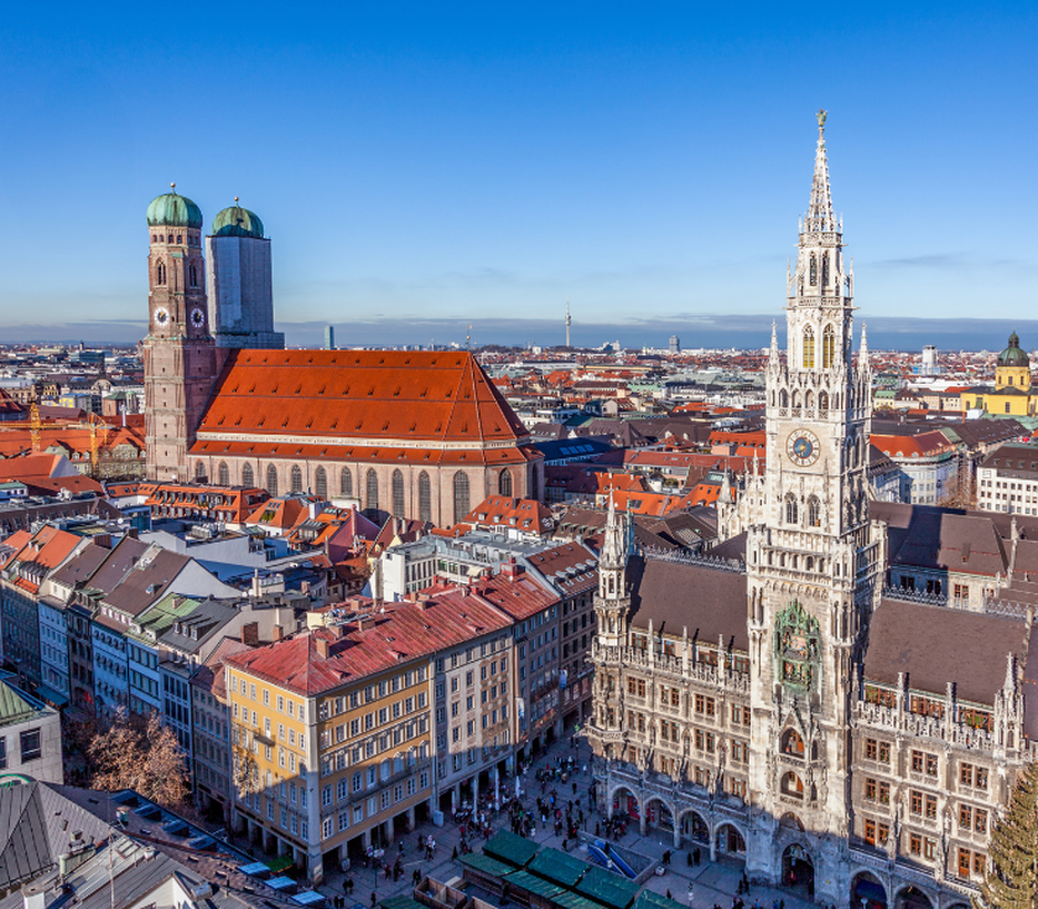 Aerial view of Marienplatz in Munich with the Frauenkirche and New Town Hall, surrounded by historic buildings under a clear blue sky.