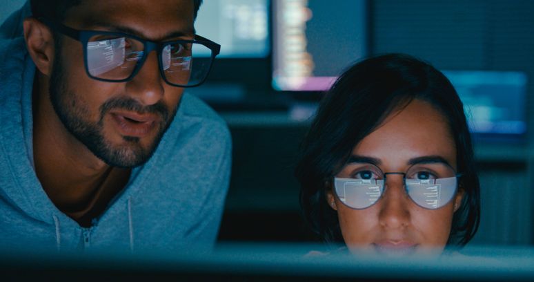 Closeup of Tech team professionals collaborate discuss software development strategies late night in modern office. Software developer, artificial intelligence and programming concept