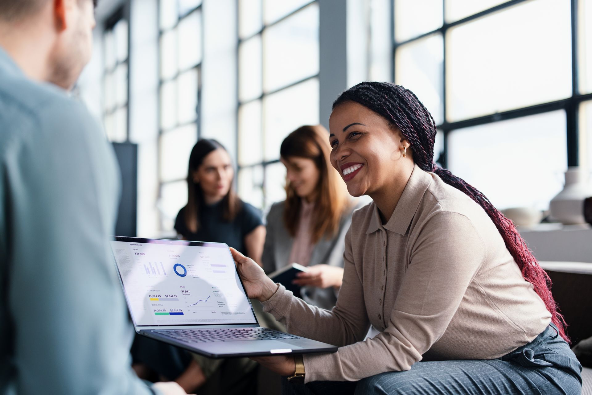 Team of professionals in a meeting, sharing a presentation on a laptop while discussing strategies.