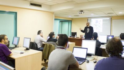 photograph of classroom of students being taught by teacher standing at the front
