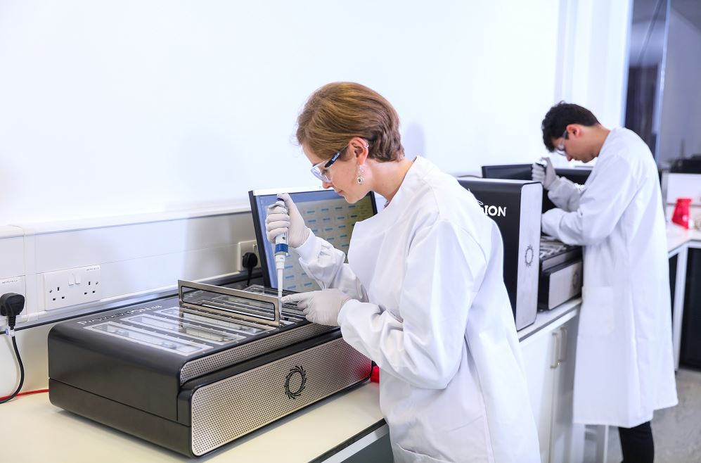 A scientist in a lab loading a sample onto a GridION sequencer flow cell
