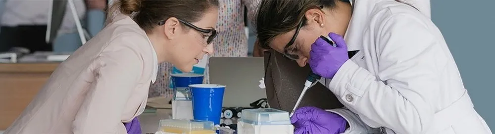 Two scientists practice loading a flow cell with a pipette