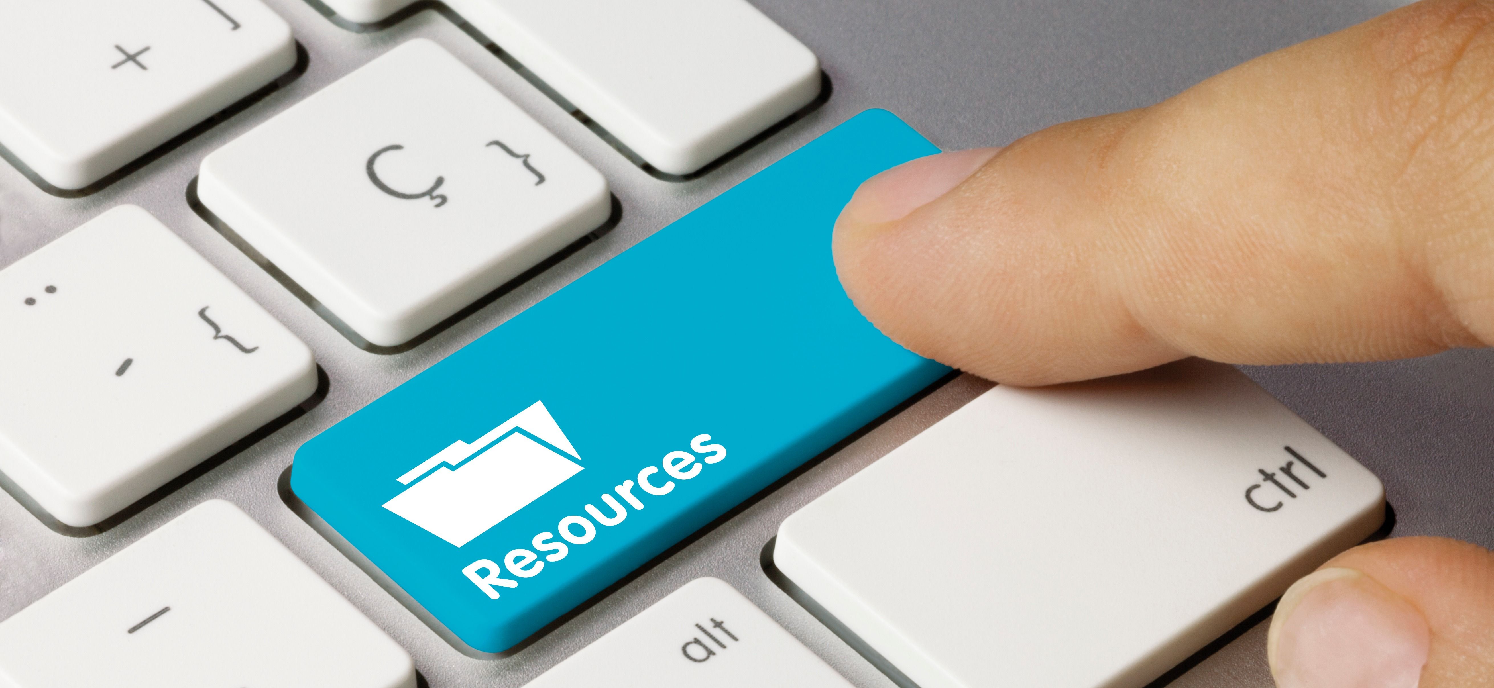 A finger pressing a 'resources' button on a keyboard