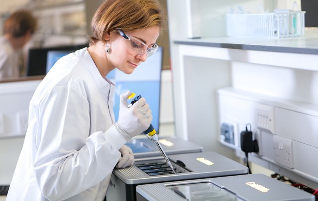 A scientist in a lab pipetting a sample into a GridION