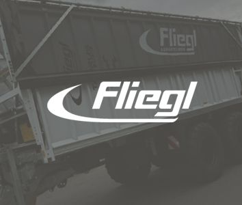 A trailer with the "Fliegl" logo prominently displayed on its side against a slightly blurred background.