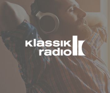 Man wearing headphones, relaxing with arms behind his head; "Klassik Radio" logo overlaid on image.