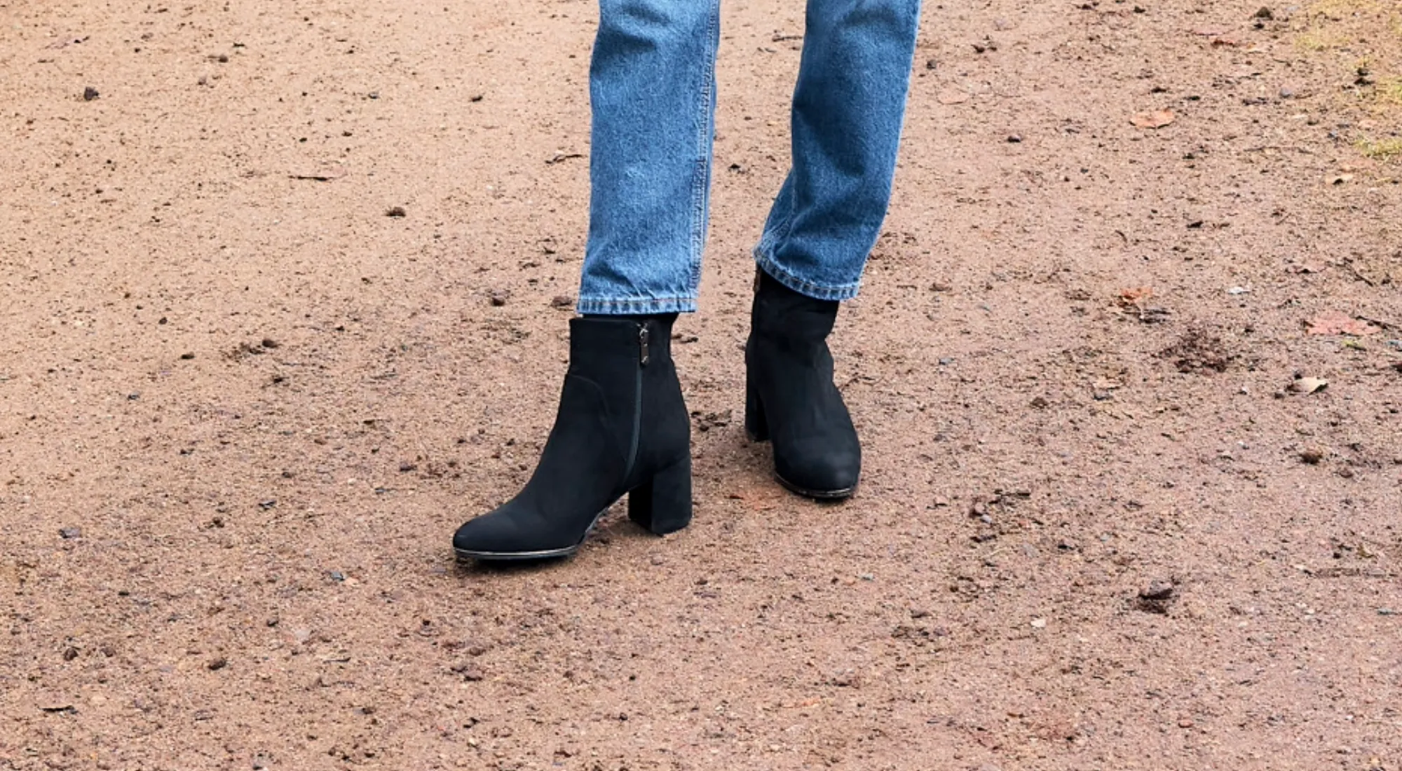 Schwarze Wildleder-Ankle Boots mit Blockabsatz und Reißverschluss, getragen mit blauen Jeans auf Waldweg, elegante Herbst-Schuhe