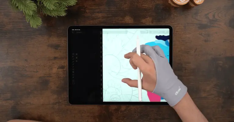 Male hands drawing on an iPad positioned on a wooden table