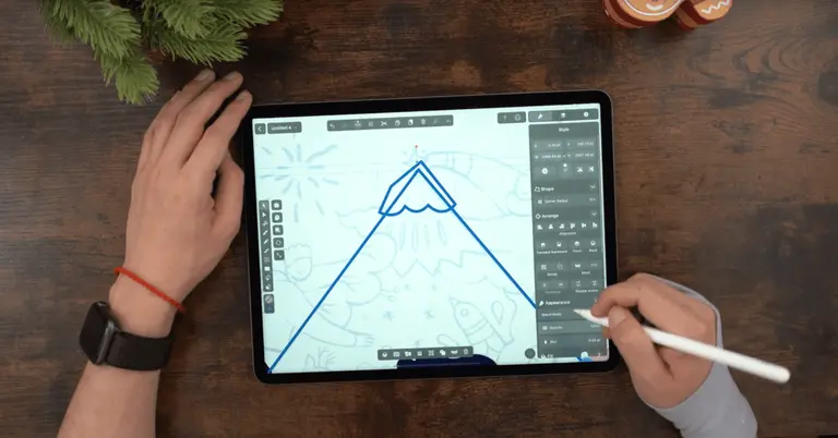 Male hands drawing on an iPad positioned on a wooden table