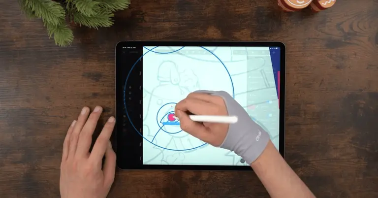 Male hands drawing on an iPad positioned on a wooden table