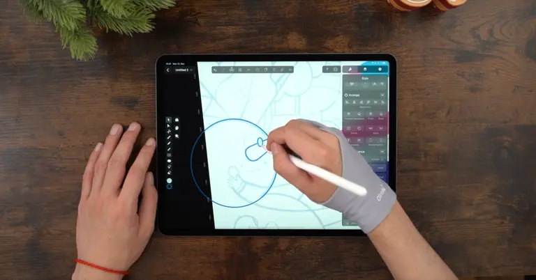 Male hands drawing on an iPad positioned on a wooden table
