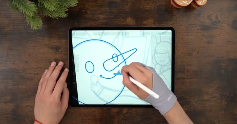 Male hands drawing on an iPad positioned on a wooden table