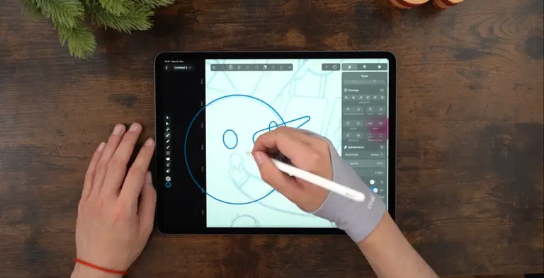 Male hands drawing on an iPad positioned on a wooden table