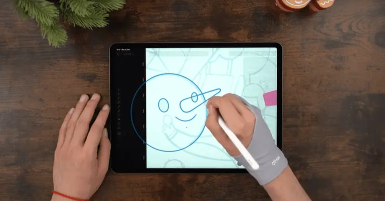 Male hands drawing on an iPad positioned on a wooden table