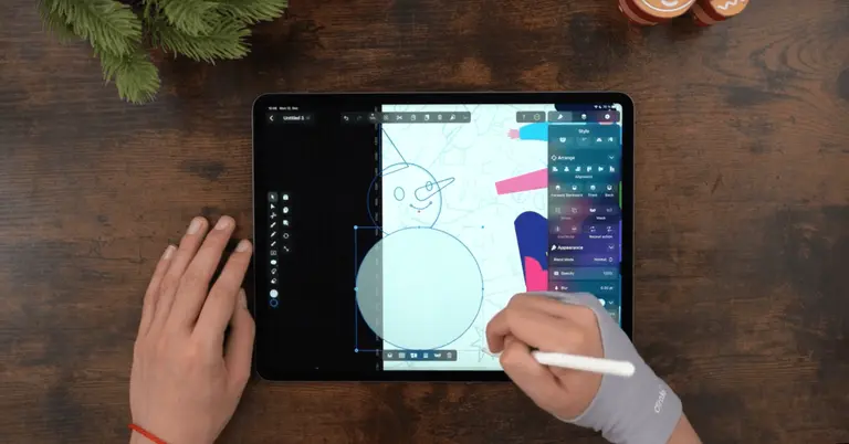 Male hands drawing on an iPad positioned on a wooden table