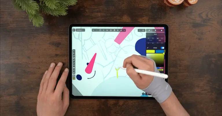 Male hands drawing on an iPad positioned on a wooden table