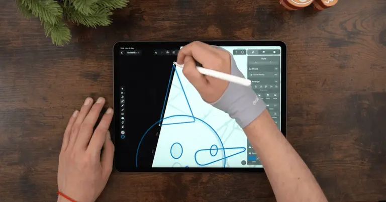 Male hands drawing on an iPad positioned on a wooden table