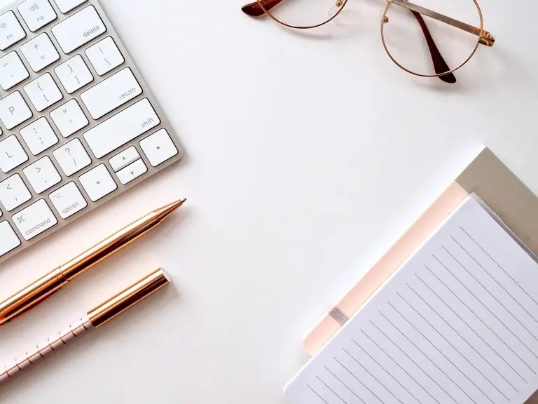Mac keyboard and notepad with glasses