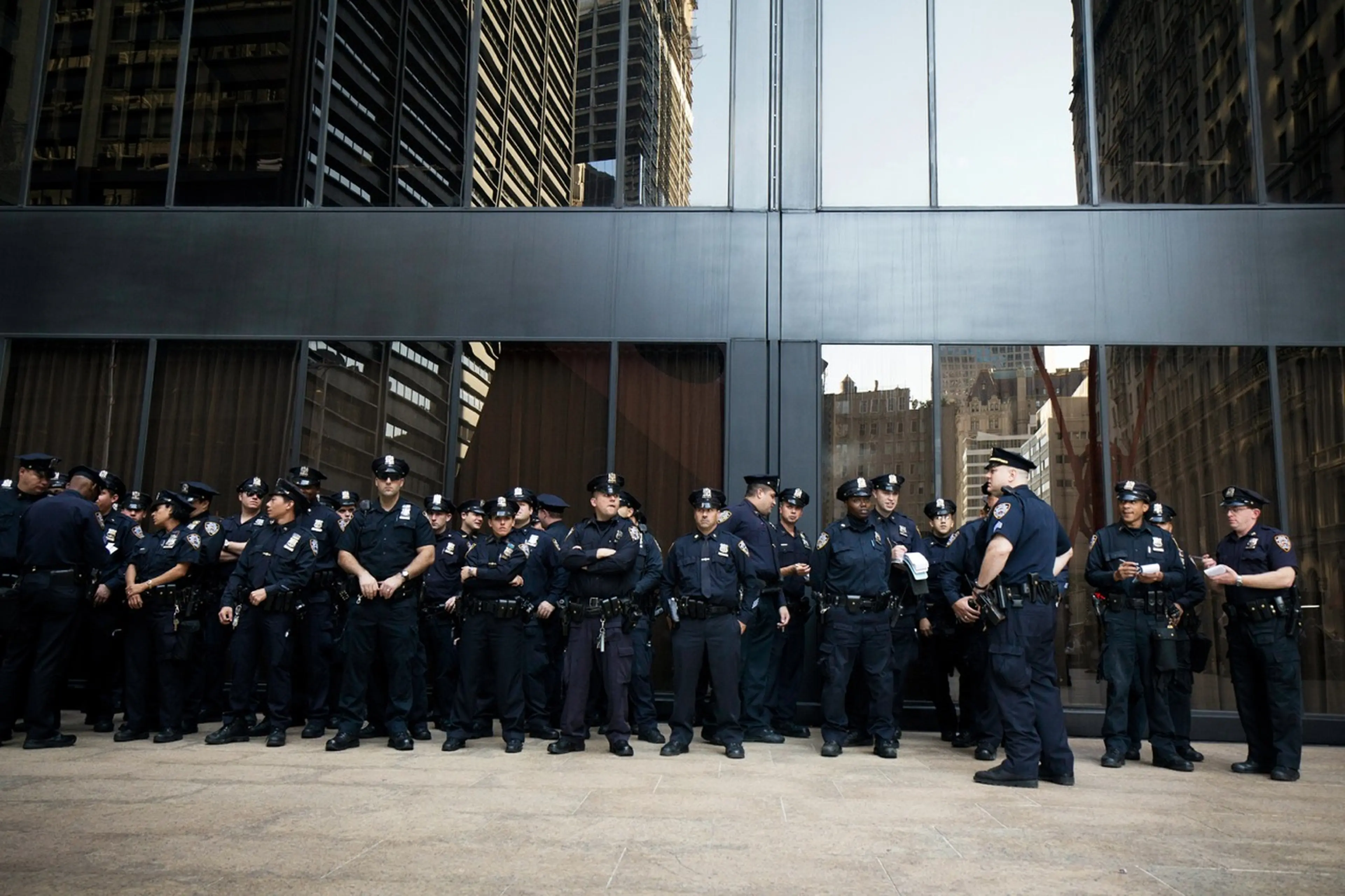 A group of police officers standing in front of a grey building.