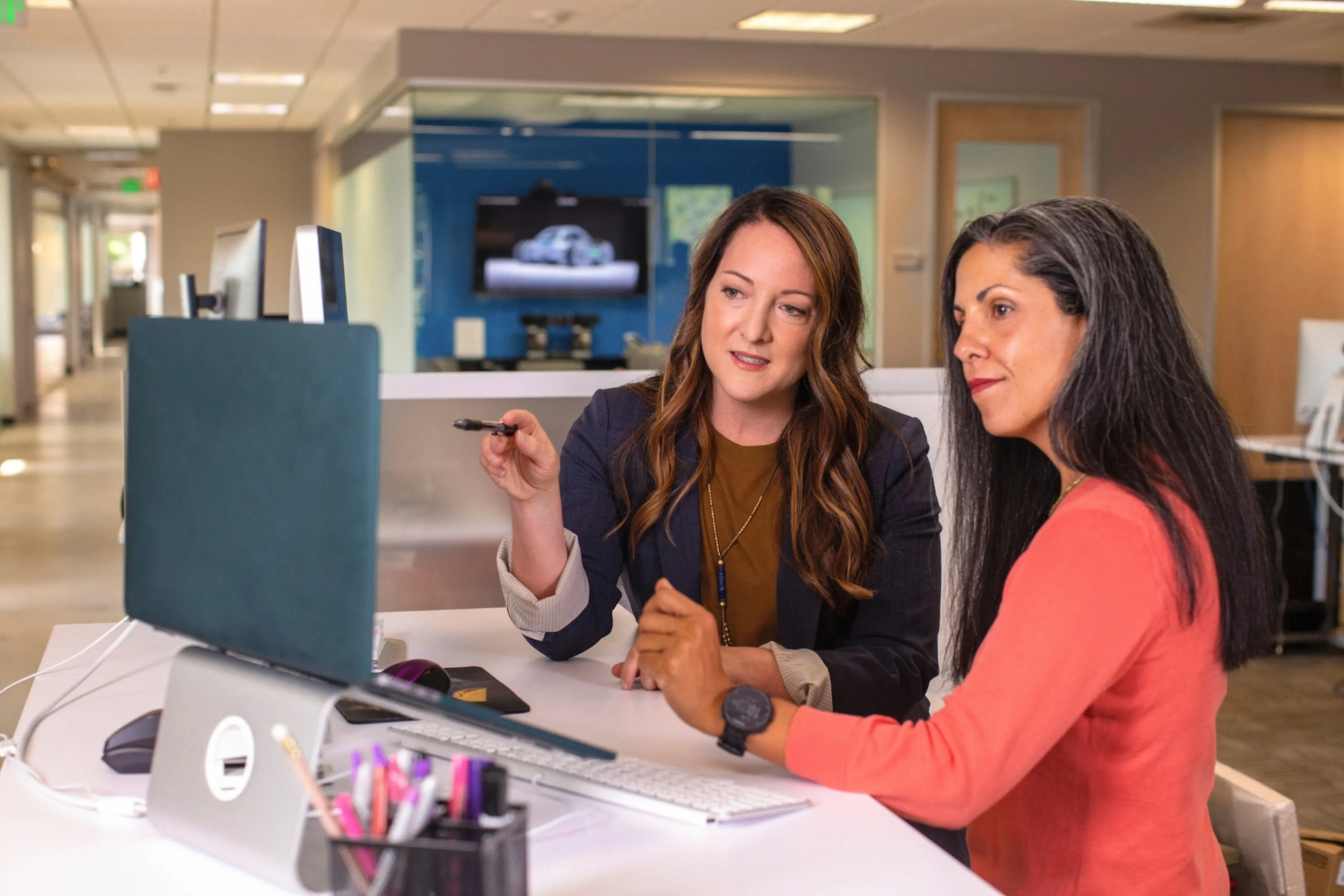 Two lawyers discussing a case; one of them is pointing at a laptop screen.