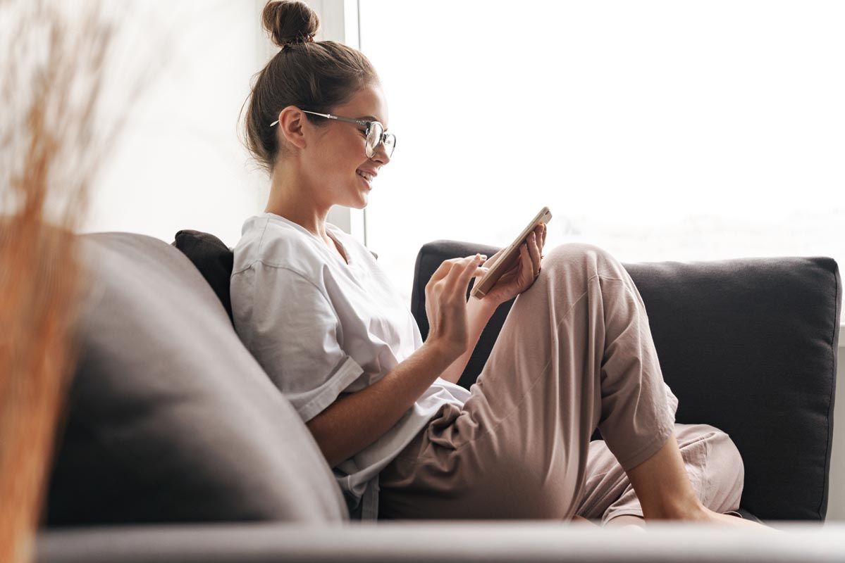 woman in sofa using her smartphone