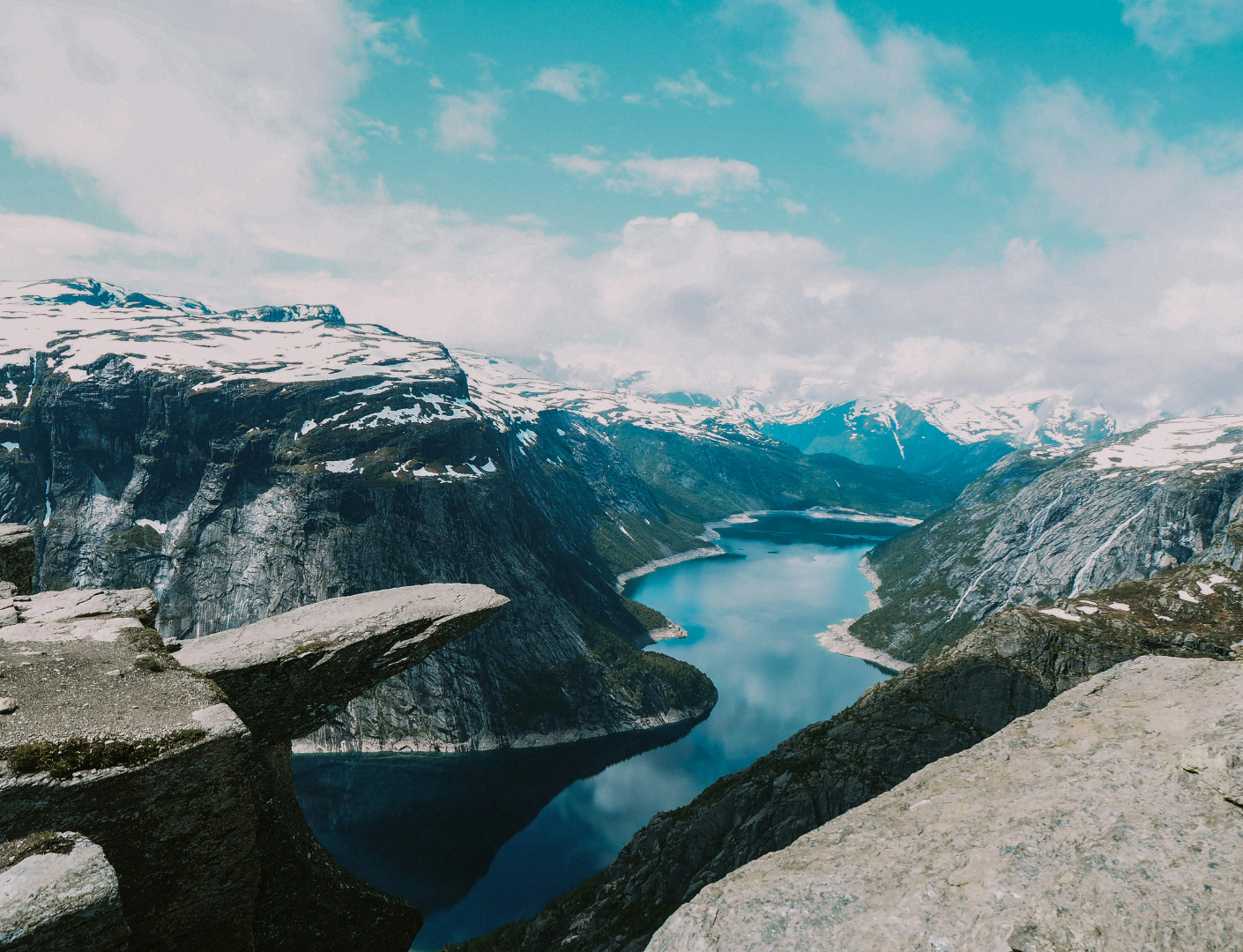uitstekende rots boven fjord en besneeuwde bergen