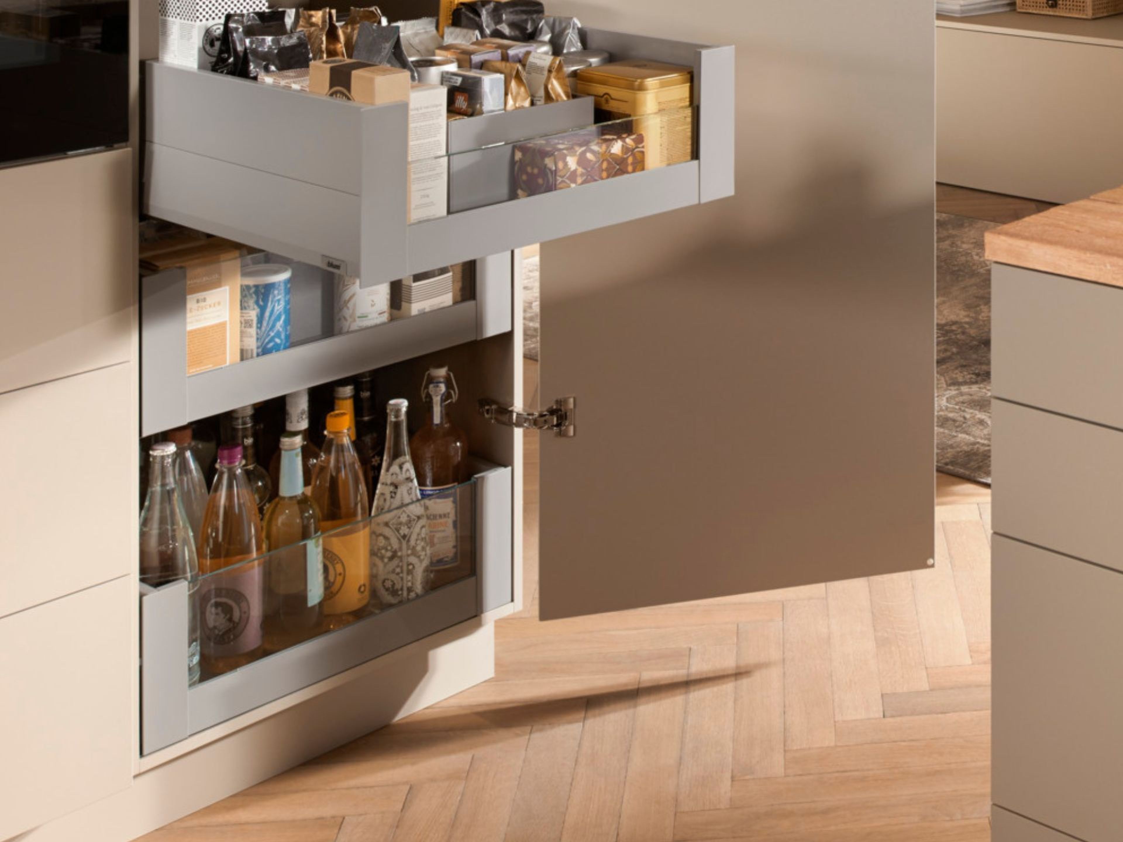 A bottom drawer filled with bottles in a pantry cabinet